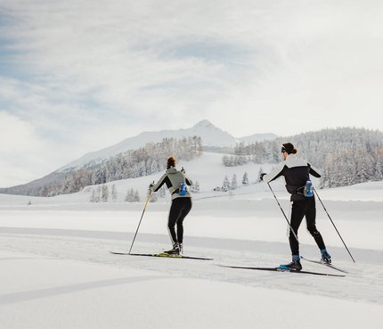 Zwei Personen beim Langlaufen in verschneiter Berglandschaft