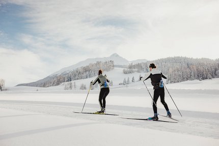 Zwei Personen beim Langlaufen in verschneiter Berglandschaft