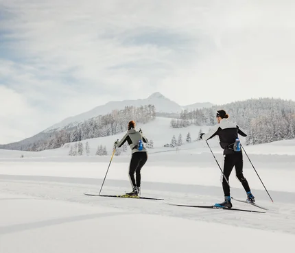 Zwei Personen beim Langlaufen in verschneiter Berglandschaft