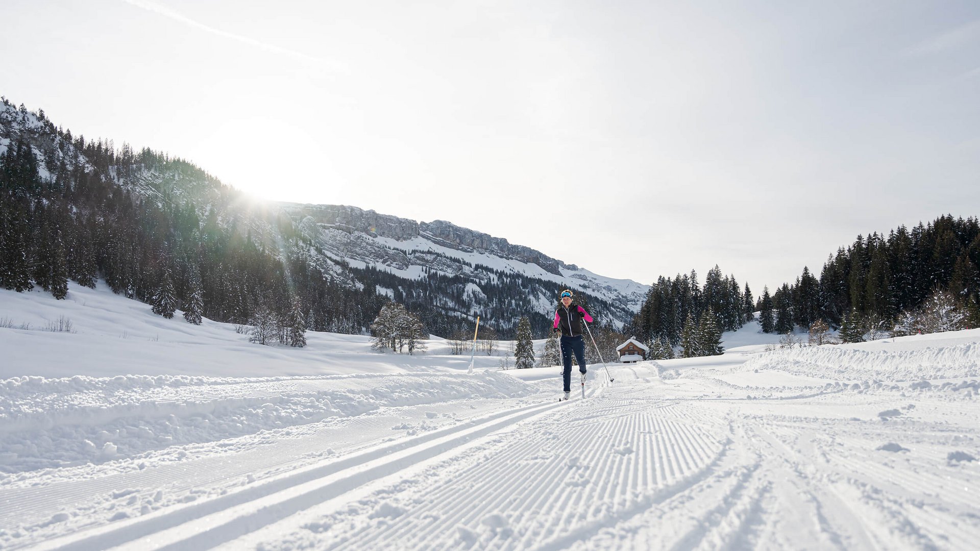 Person cross-country skiing on a snowy trail with mountains in the background