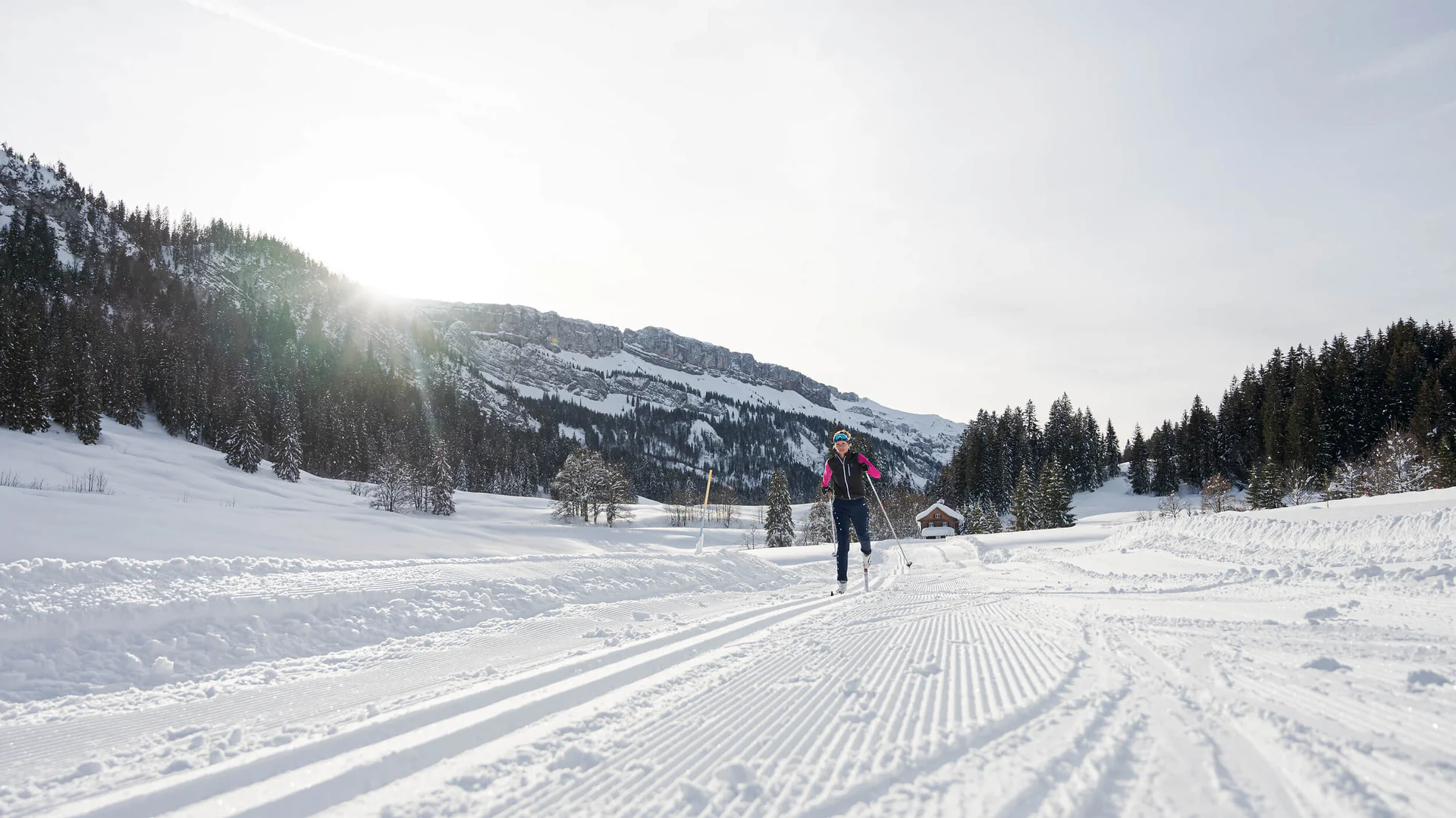 Loipen & Loipenbericht © Frithjof Kjer Person beim Skilanglauf auf verschneiter Loipe vor Bergkulisse bei Sonnenschein