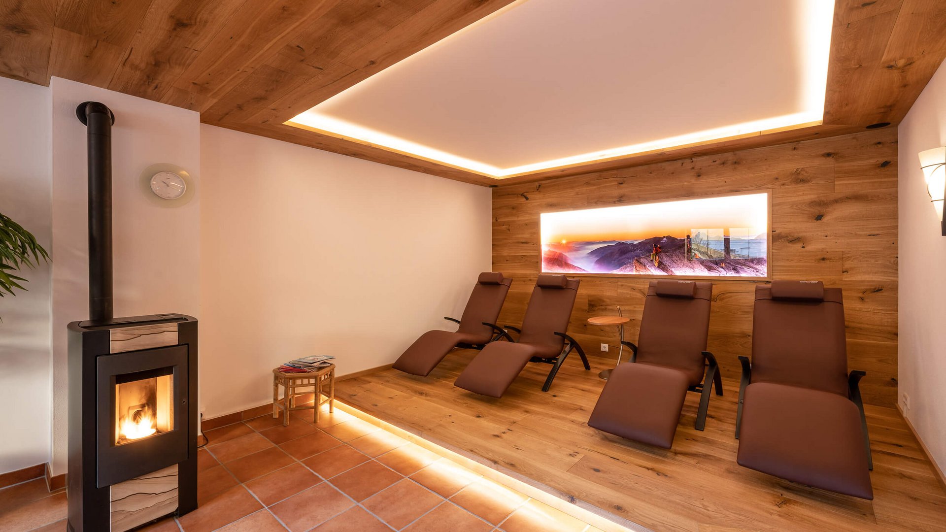 Relaxation room with wood paneling, lounge chairs, and wood stove