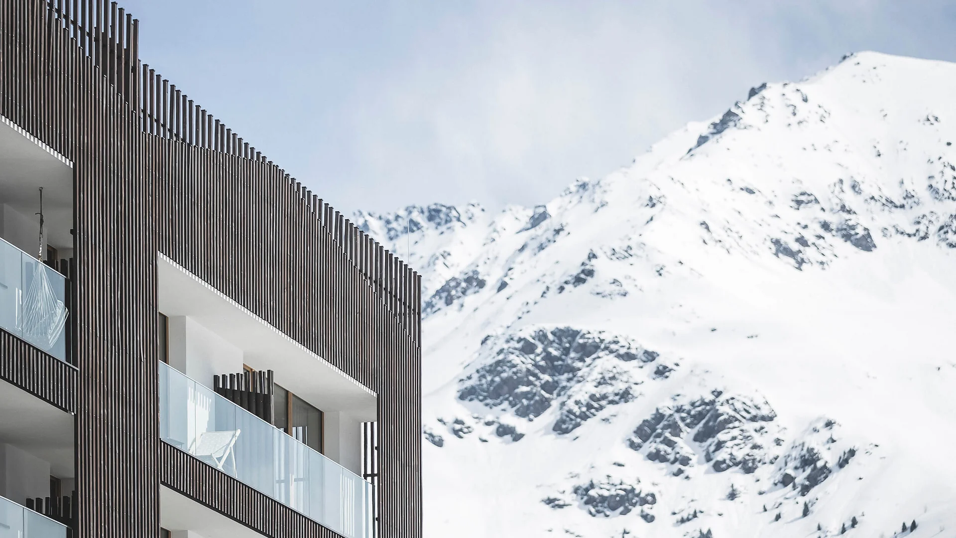 Modern balcony with glass railings against snowy mountain backdrop