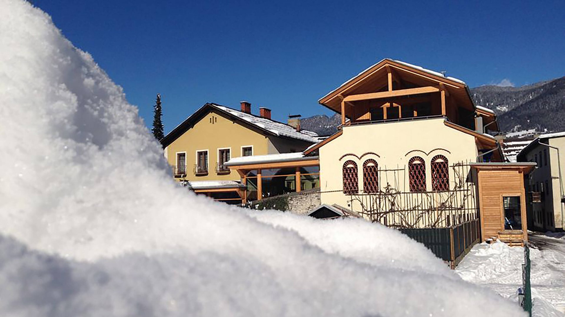 Snow-covered houses under clear blue sky in the mountains