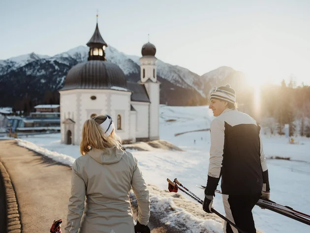 Schneesicher langlaufen: Wo Snowfarming in Österreich frühen Saisonstart möglich macht
© Alex Moling Zwei Langläufer im Winter vor einer Kirche in den Bergen bei Sonnenuntergang