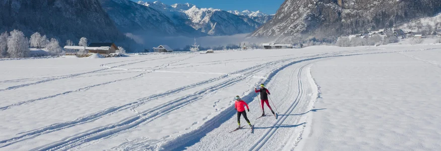 Slowenien: Geheimtipp für Nordische Wintersportler © Mojca Odar Zwei Langläufer auf schneebedeckter Loipe vor Bergen bei blauem Himmel