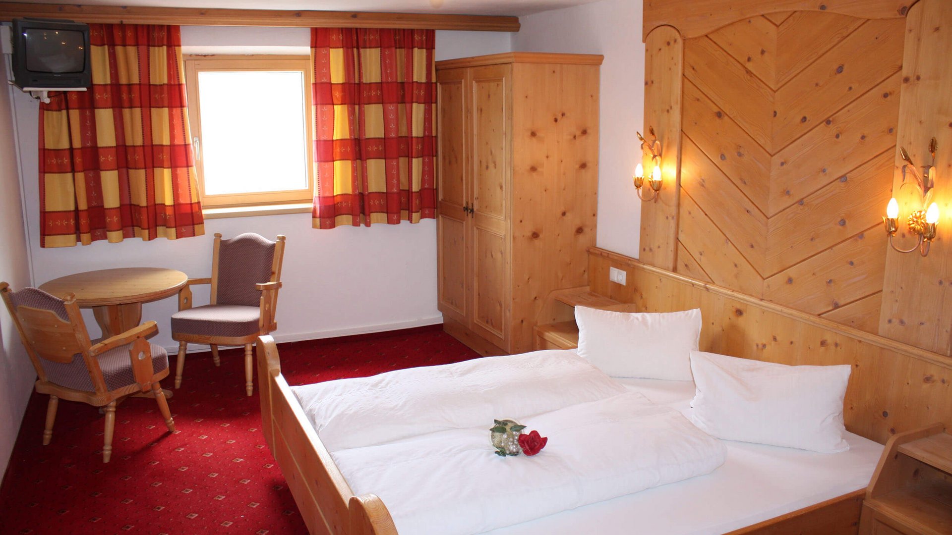 Cozy hotel room with double bed, wooden furniture, and red carpet