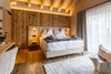 Sammelanfragen © Simone Imperioli Gemütliches Hotelzimmer mit Holzwand, Doppelbett und großem Fenster