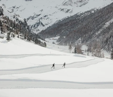 nordic³ © Alex Moling Zwei Skifahrer auf einer Spur in schneebedecktem Tal vor verschneiten Bergen