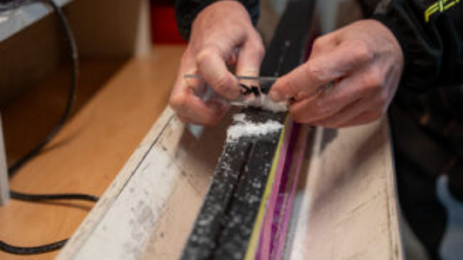 Person trägt Wachs auf die Unterseite eines Skis auf