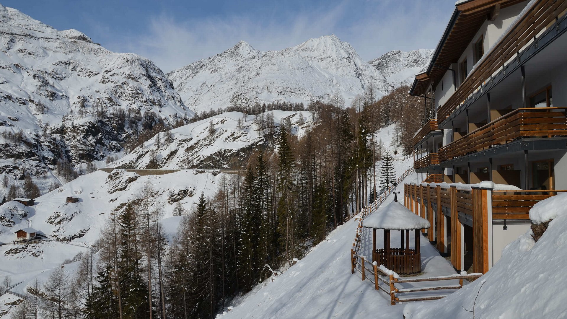 Schneebedeckte Berge und moderne Berghütte mit Holzveranda im Winter