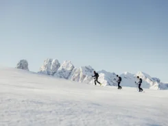 Drei Skitourengeher wandern im Schnee vor schneebedeckten Bergen