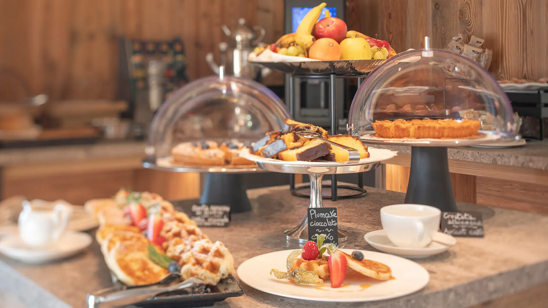 Various cakes and fruit on a buffet with coffee cups