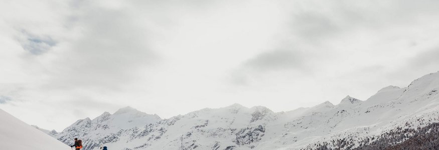 Zwei Skifahrer steigen einen schneebedeckten Hügel in den Bergen hinauf