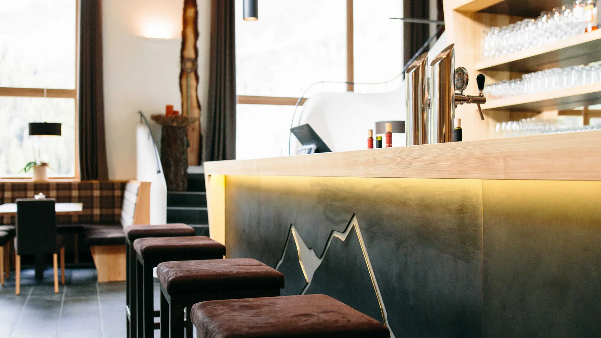 Moderner Barbereich mit Hockern und großen Fenstern in einem Restaurant