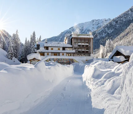 Schneebedeckter Weg zu einem Hotel im sonnigen Wintergebirge