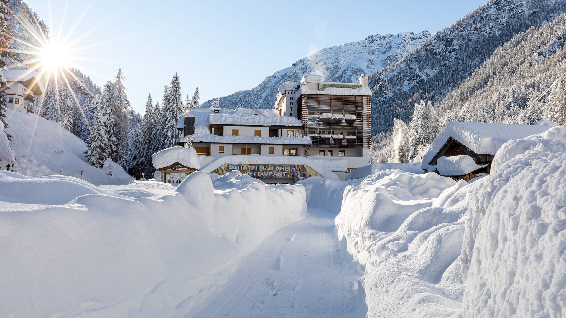 Schneebedeckter Weg zu einem Hotel im sonnigen Wintergebirge
