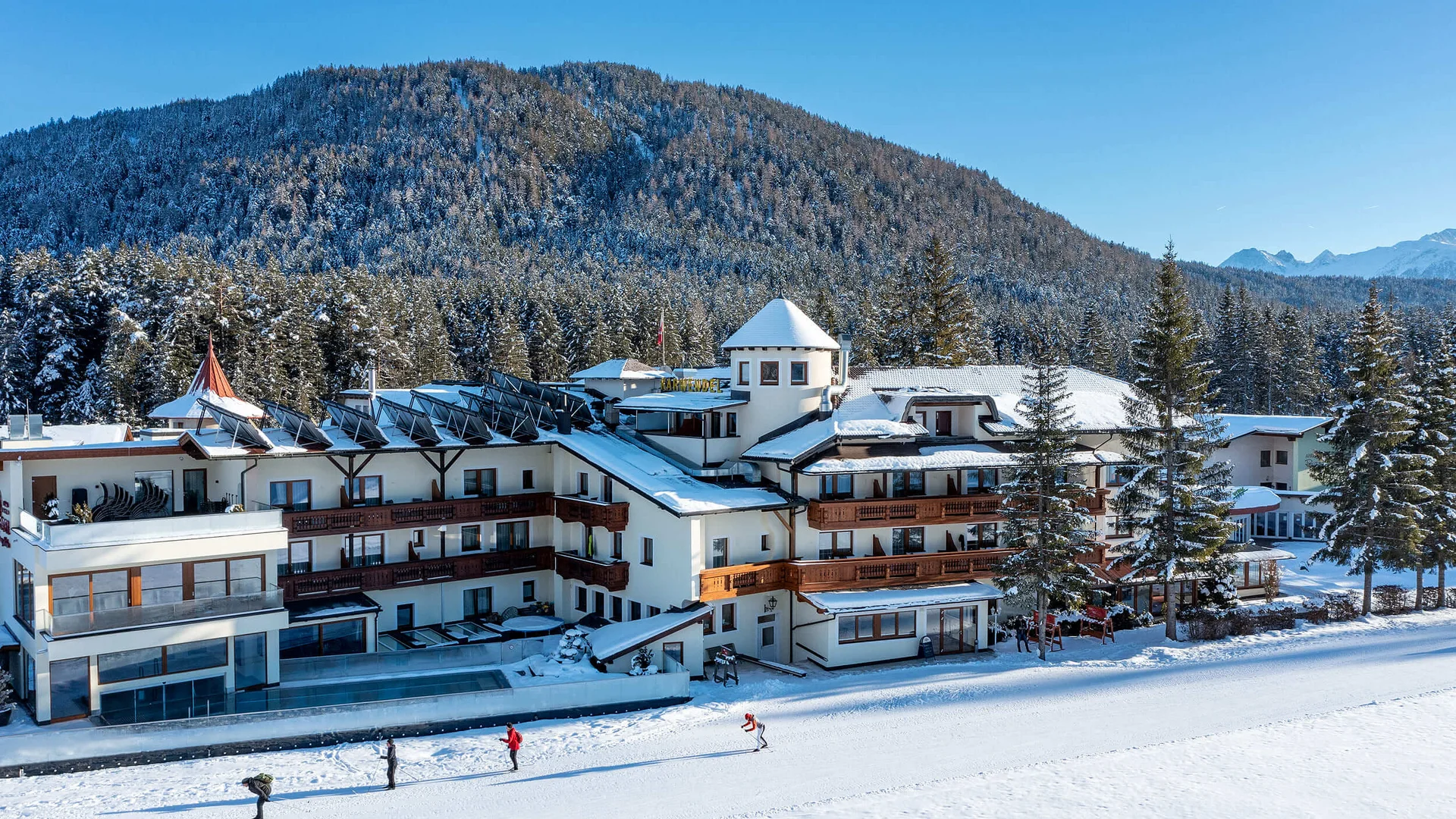 Hotel building in snow with forested mountain and clear blue sky