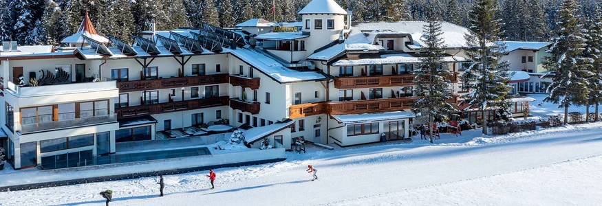 Hotel building in snow with forested mountain and clear blue sky