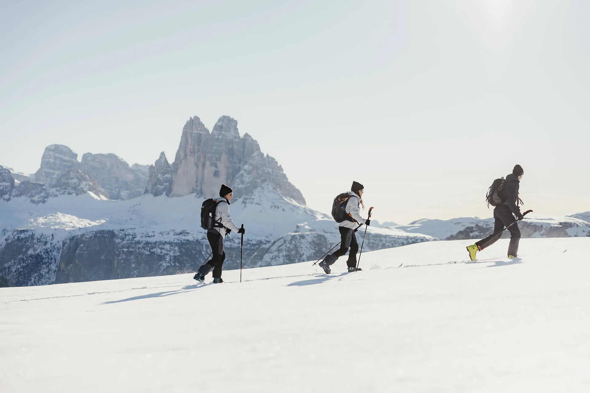 Drei Menschen beim Schneeschuhwandern vor Bergen im Schnee