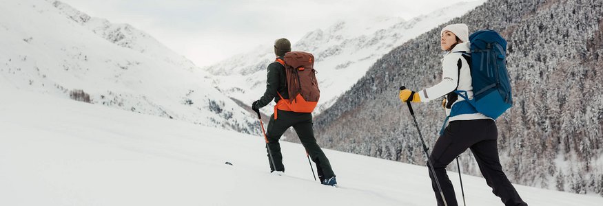 Zwei Wanderer mit Rucksäcken wandern im verschneiten Berggebiet