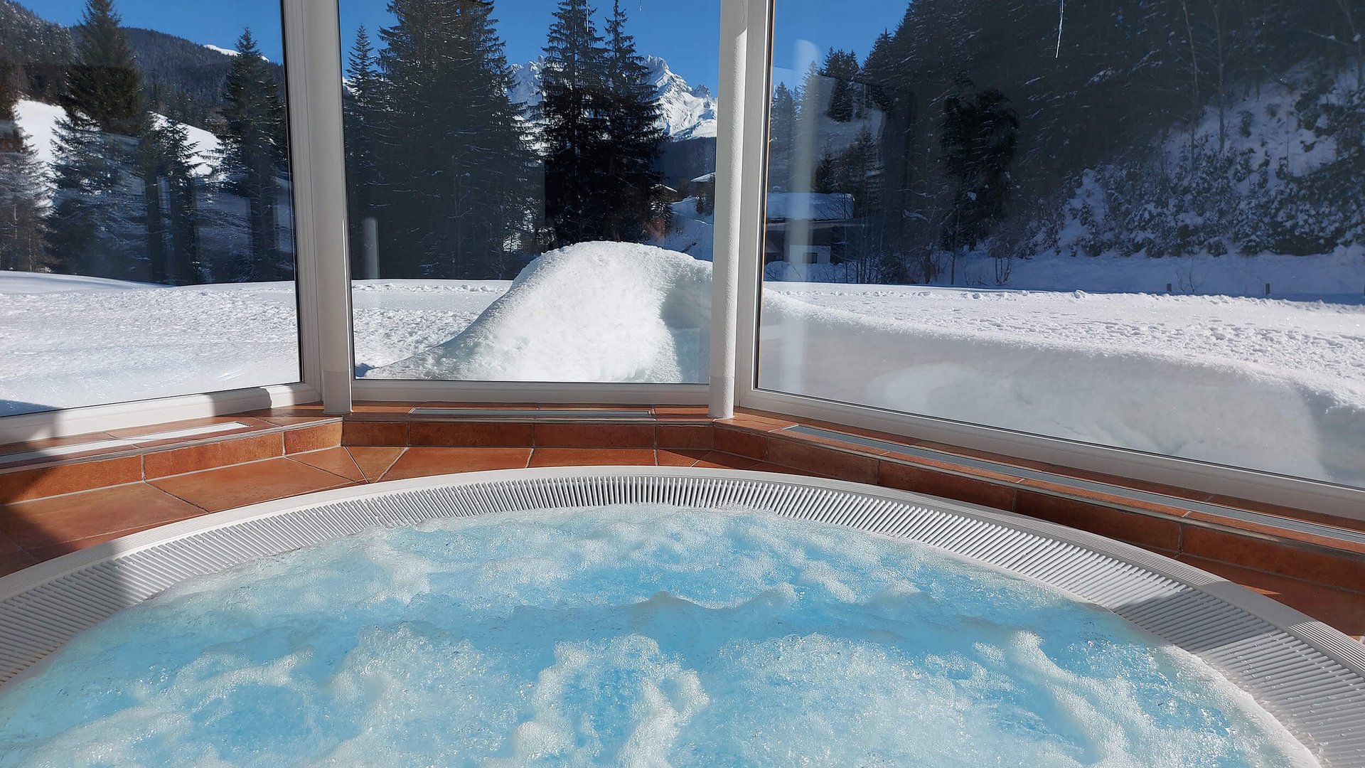 Whirlpool innen mit Aussicht auf verschneite Bäume und Berge