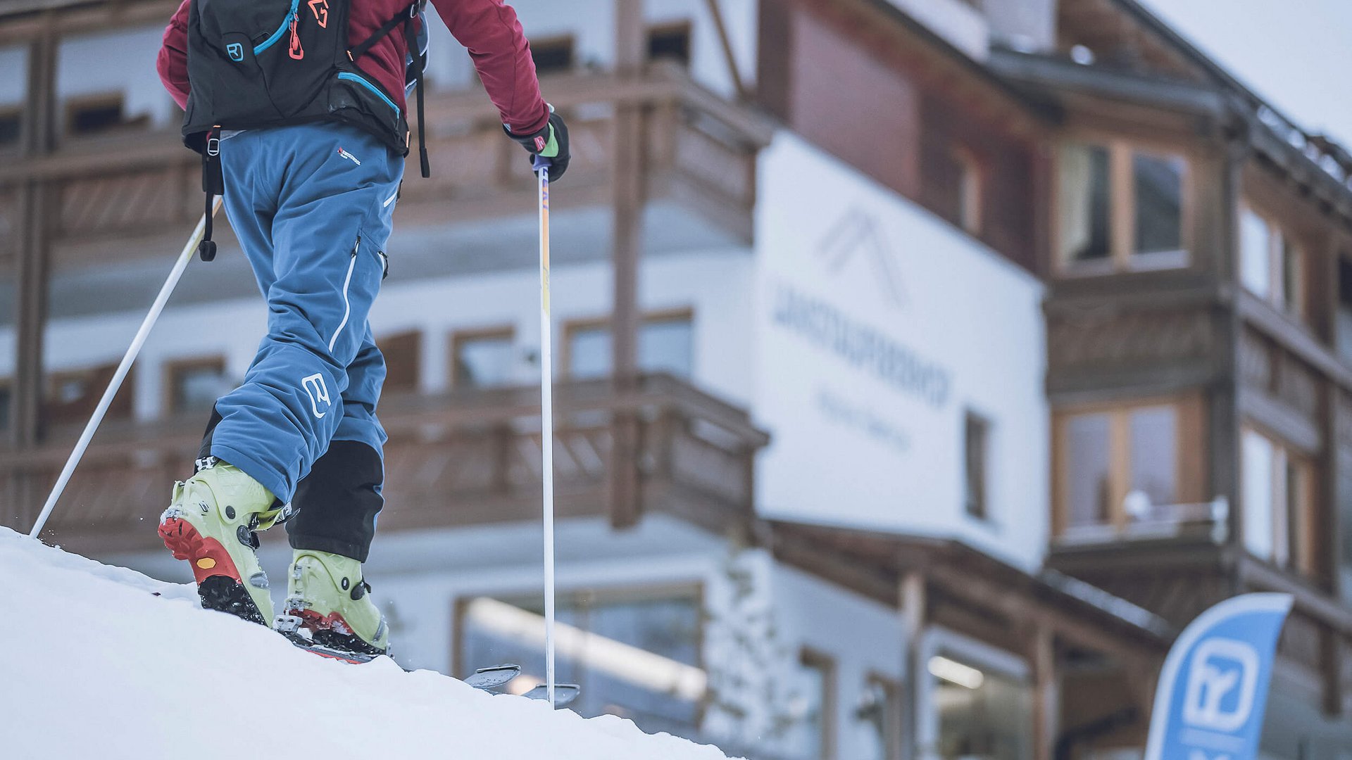 Skifahrer in Bergort vor einem Holzgebäude im Schnee
