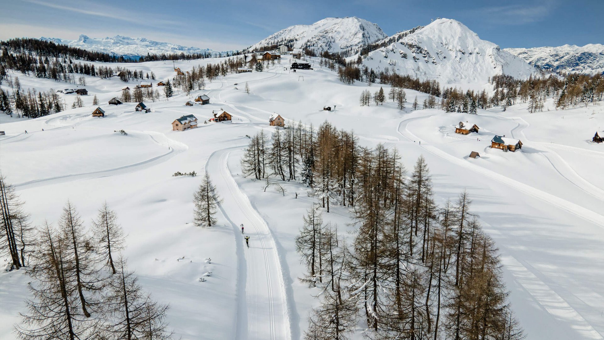 Schneebedeckte Alpen mit Chalets und Langläufern unter klarem Himmel