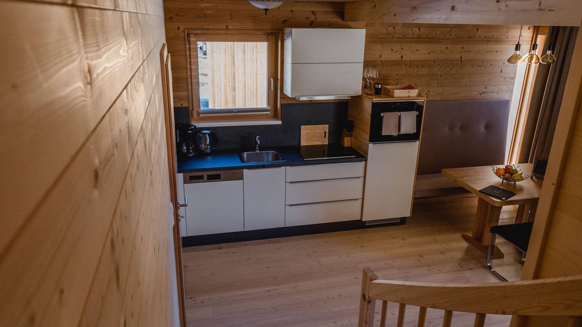 Modern kitchen and dining area with wood paneling and staircase in apartment