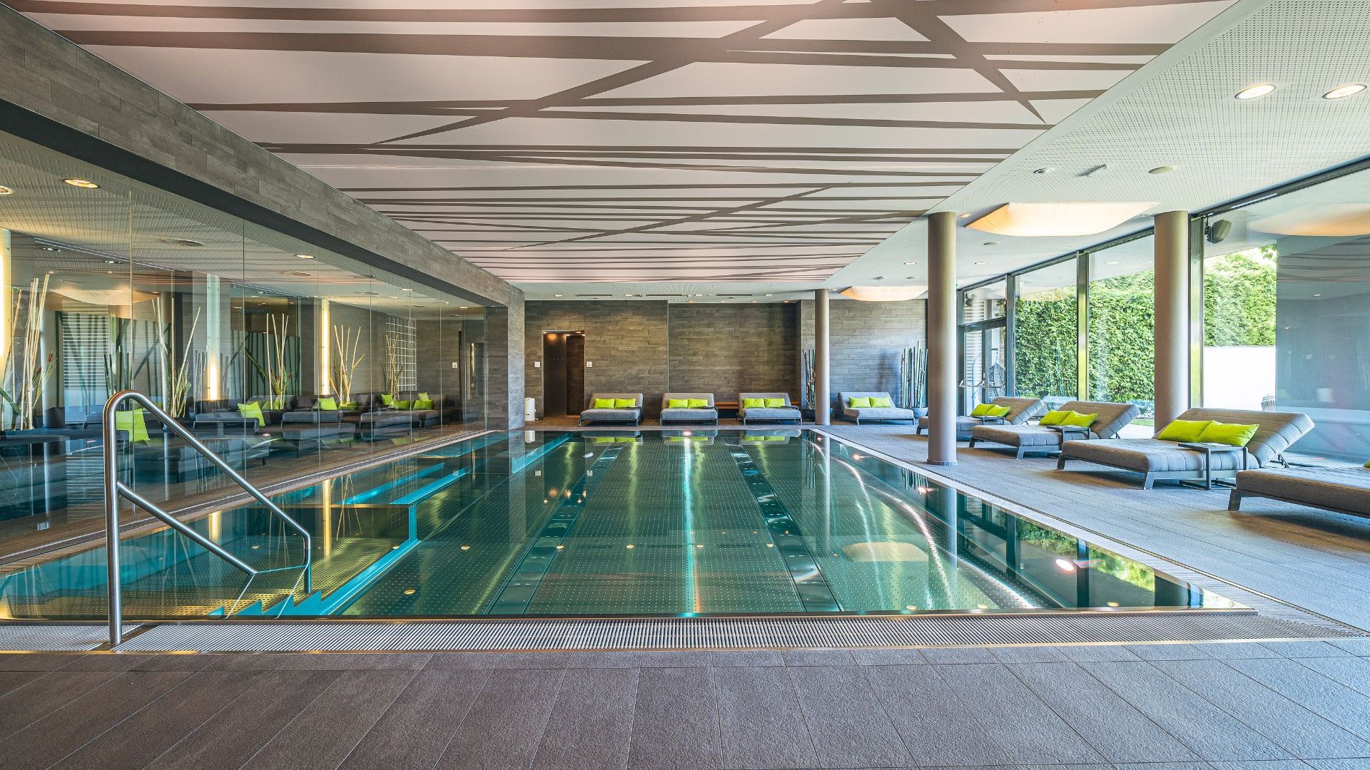 Modern indoor pool with lounge chairs and large wall mirror