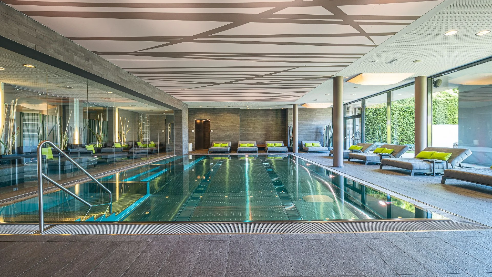 Moderner Indoor-Pool mit Liegestühlen und großem Spiegel an der Wand