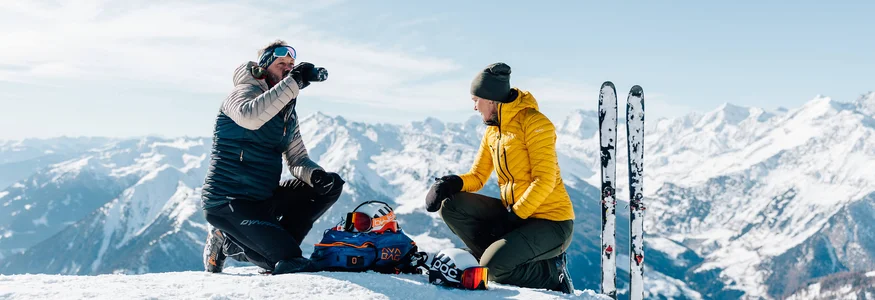 Zwei Skifahrer machen Pause im Schnee mit Bergblick
