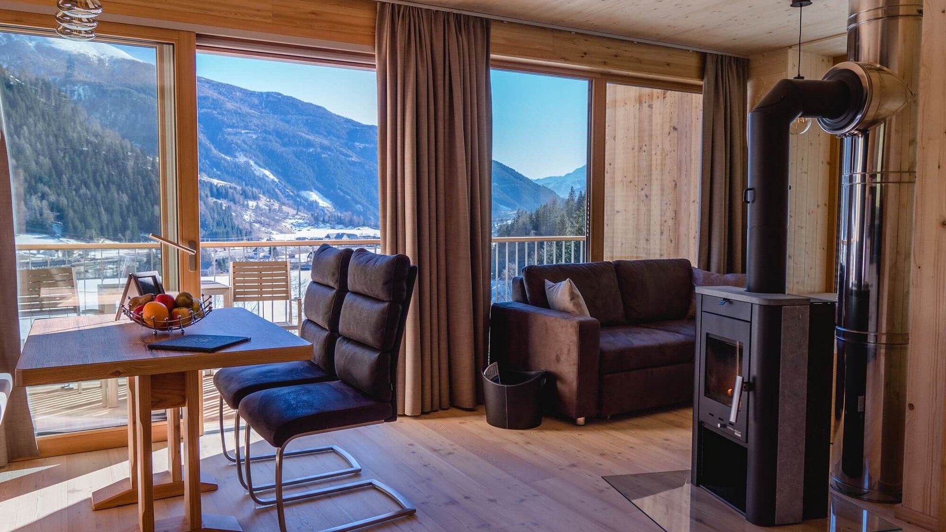 Living room with fireplace, sofa, dining table, and mountain view through large windows