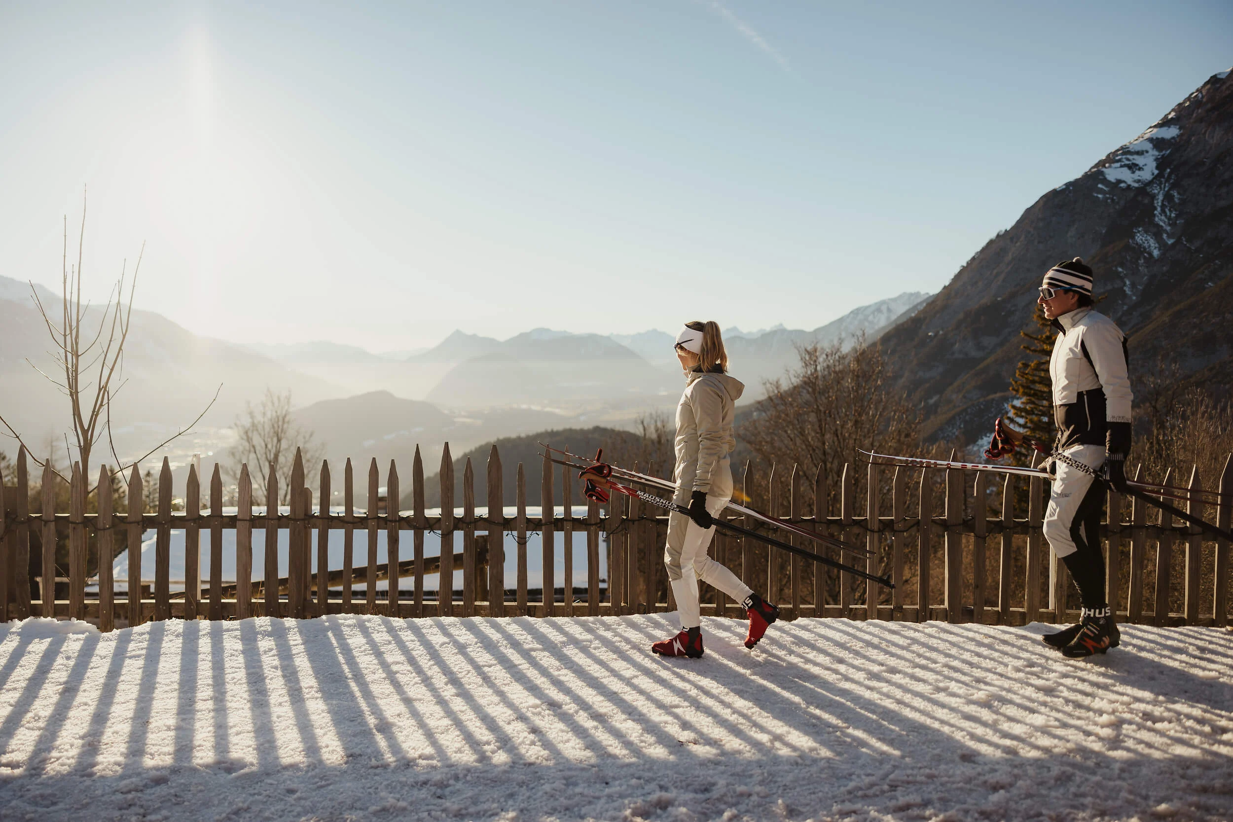 Austria © Alex Moling Two skiers walking with skis and poles on snow-covered path with mountain view