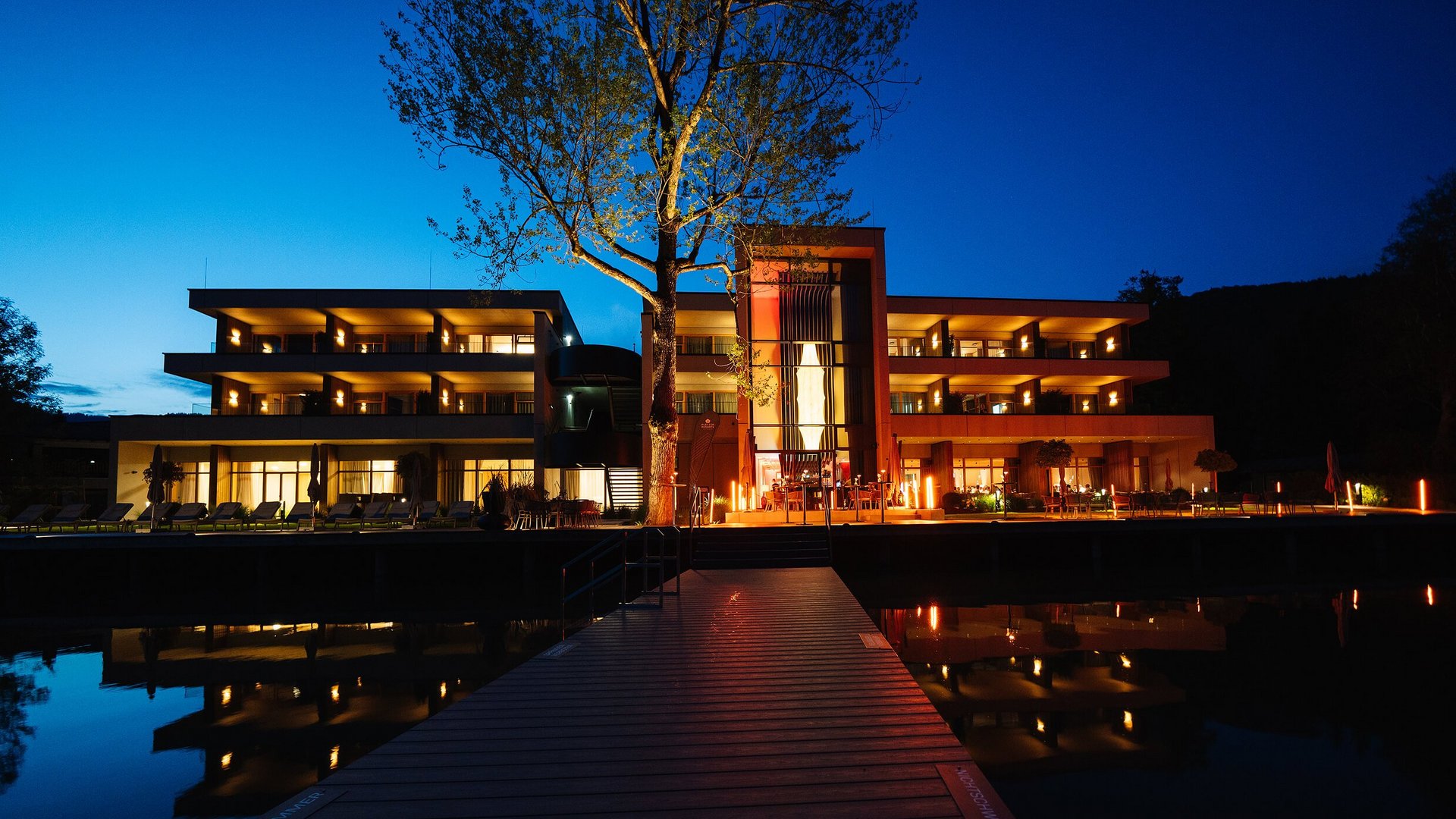 Das Walchsee Resort **** © Pletzer Resorts Beleuchtetes modernes Hotel bei Nacht mit Wasserspiegelung und Steg