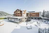 Modernes Berghotel mit verschneiter Terrasse, Liegestühlen und Außenpool