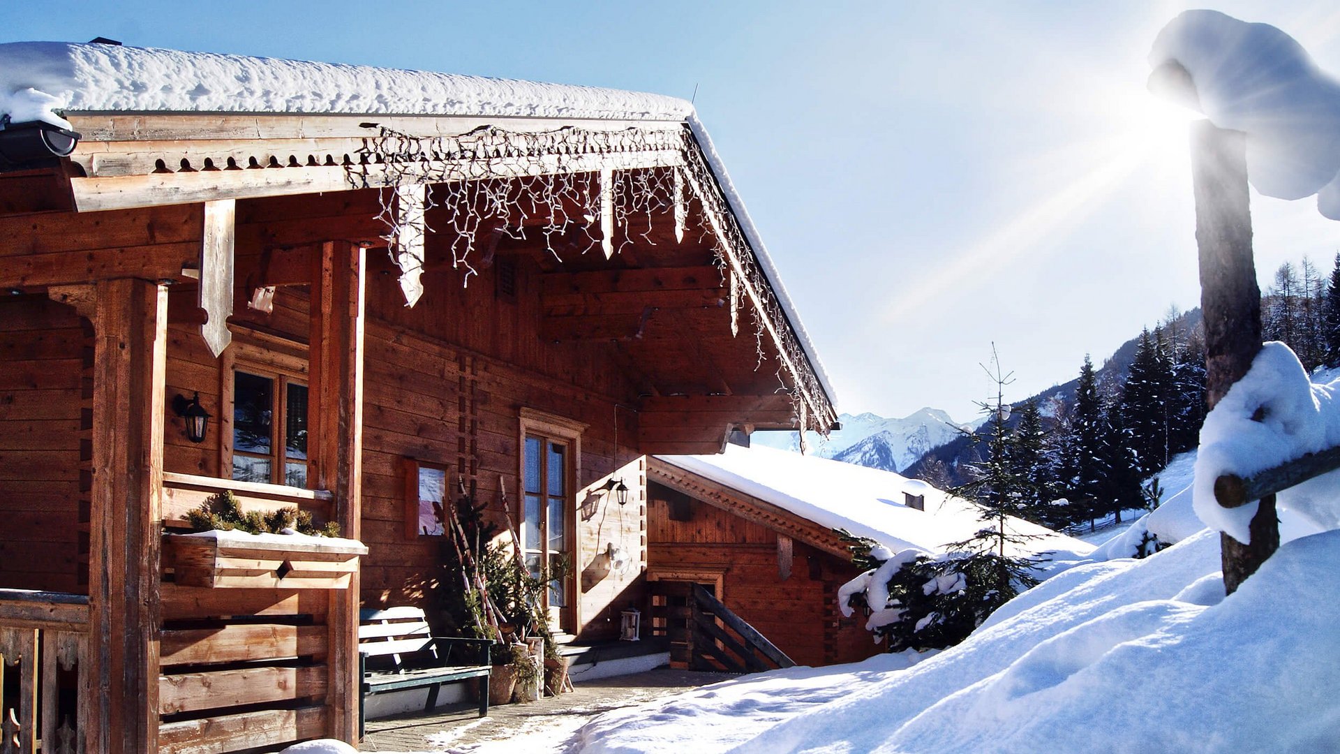 Snow-covered mountain cabin with winter sun and clear blue sky