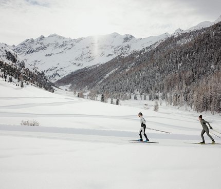Grenzen? Nicht in der nordic³-Region! © Alex Moling Zwei Personen Langlauf in verschneiter Berglandschaft mit Nadelwald