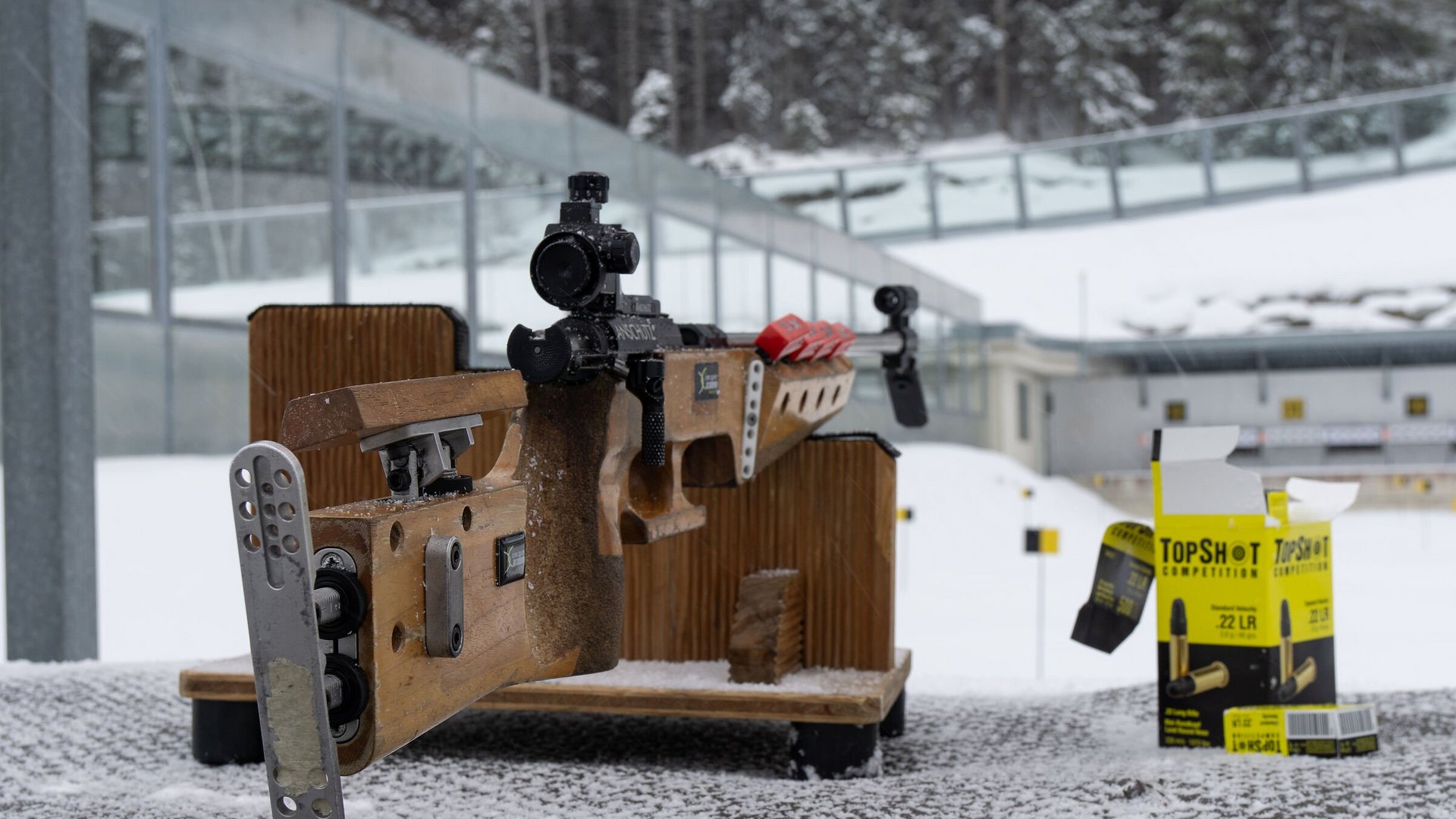 Biathlon-Schiessen-am-Stand-in-der-WM-Arena-Seefeld-c-Region-Seefeld.jpg © Region Seefeld Präzisionsgewehr auf Schneetisch mit Munition und Zielscheiben im Hintergrund