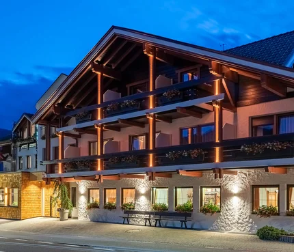 Beleuchtetes alpines Hotelgebäude in der Abenddämmerung