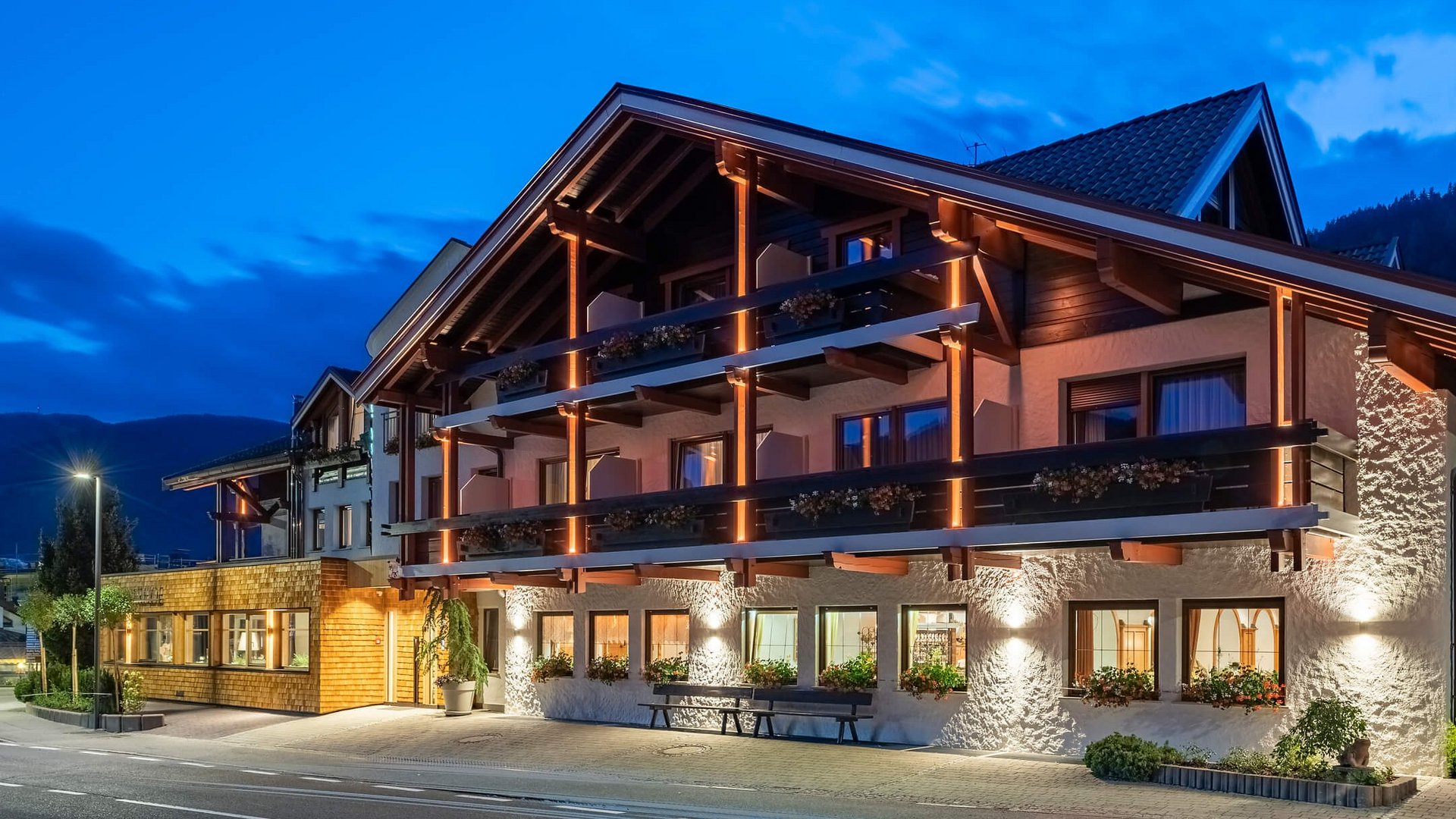 Beleuchtetes alpines Hotelgebäude in der Abenddämmerung