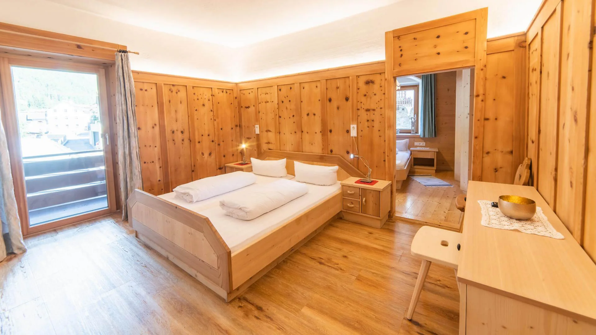 Holzgetäfeltes Schlafzimmer mit Doppelbett, Schreibtisch und Balkontür