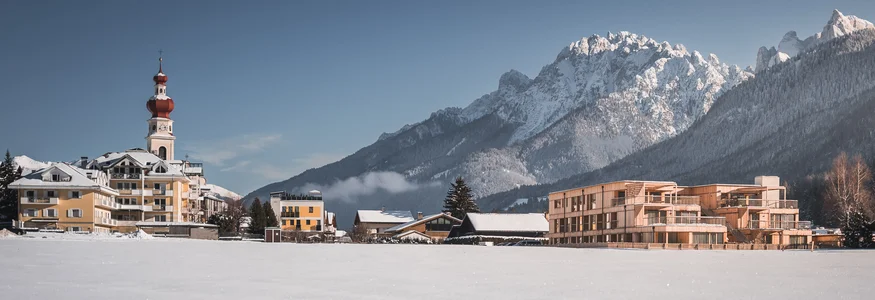Hirben Naturlaub **** © Manuel Kottersteger Schneebedecktes Dorf vor den Alpen mit Kirche und modernen Gebäuden