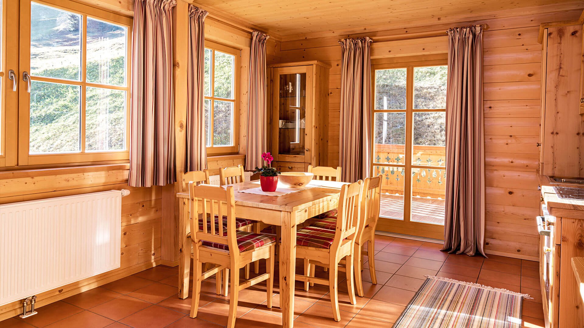 Rustic dining area with wooden furniture and curtained windows in a cabin