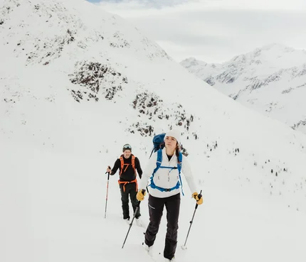Zwei Skitourengeher wandern im verschneiten Gebirge