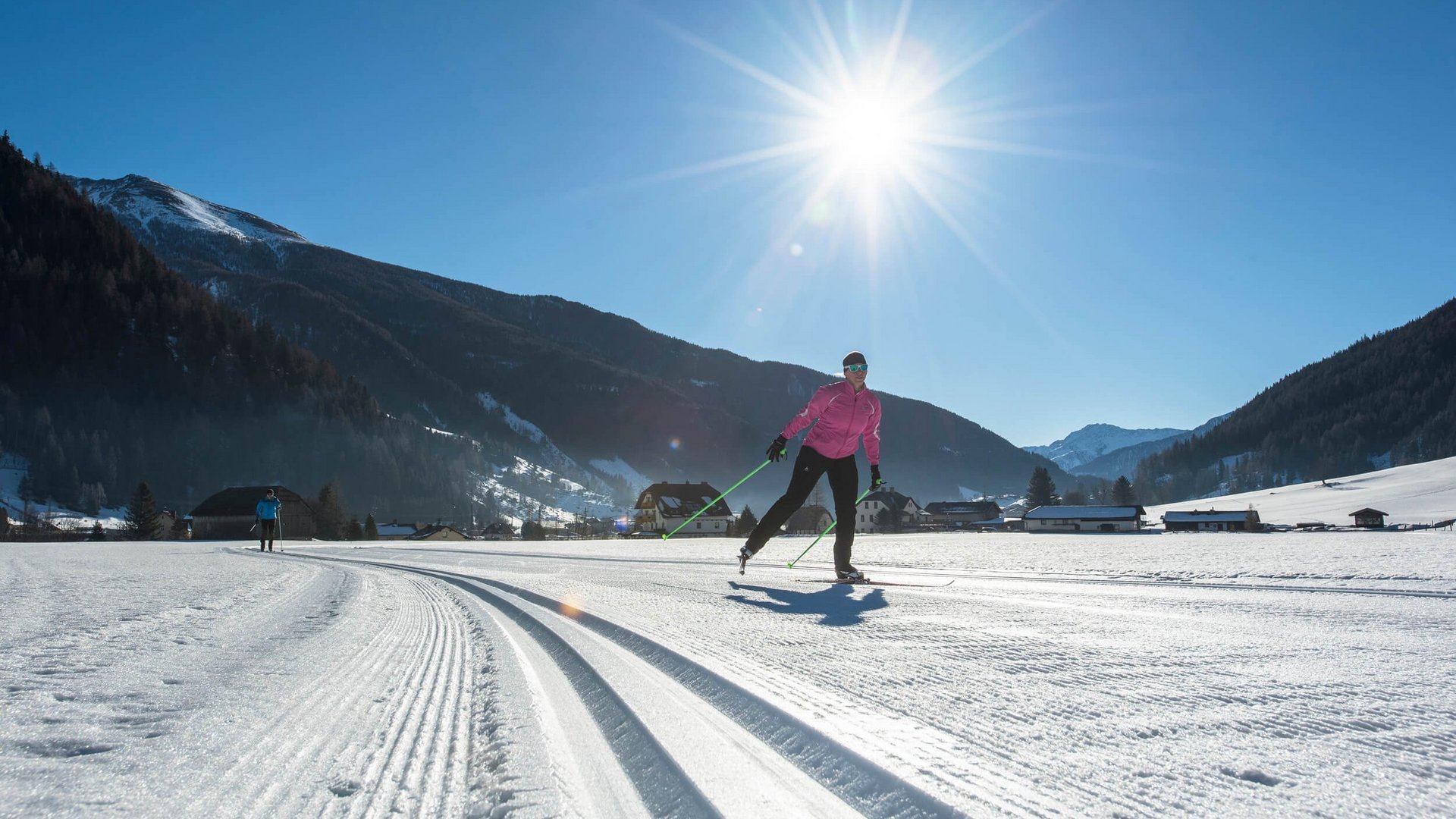Langläufer bei sonnigem Wetter in verschneiter Berglandschaft
