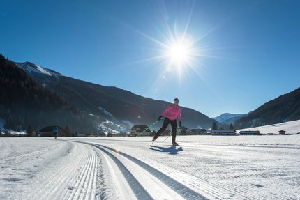 Langläufer bei sonnigem Wetter in verschneiter Berglandschaft