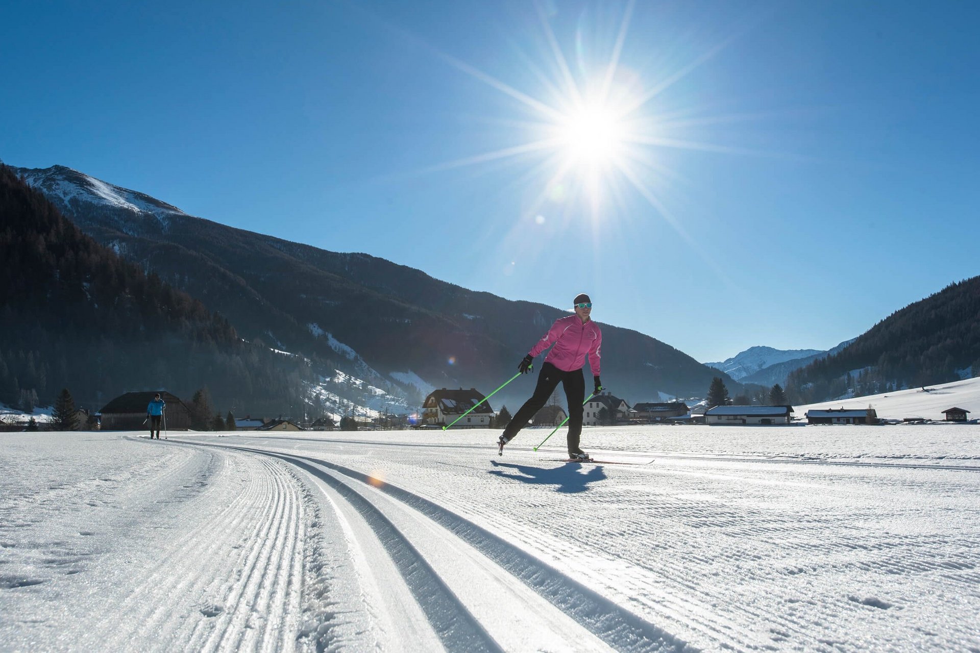 Langläufer bei sonnigem Wetter in verschneiter Berglandschaft