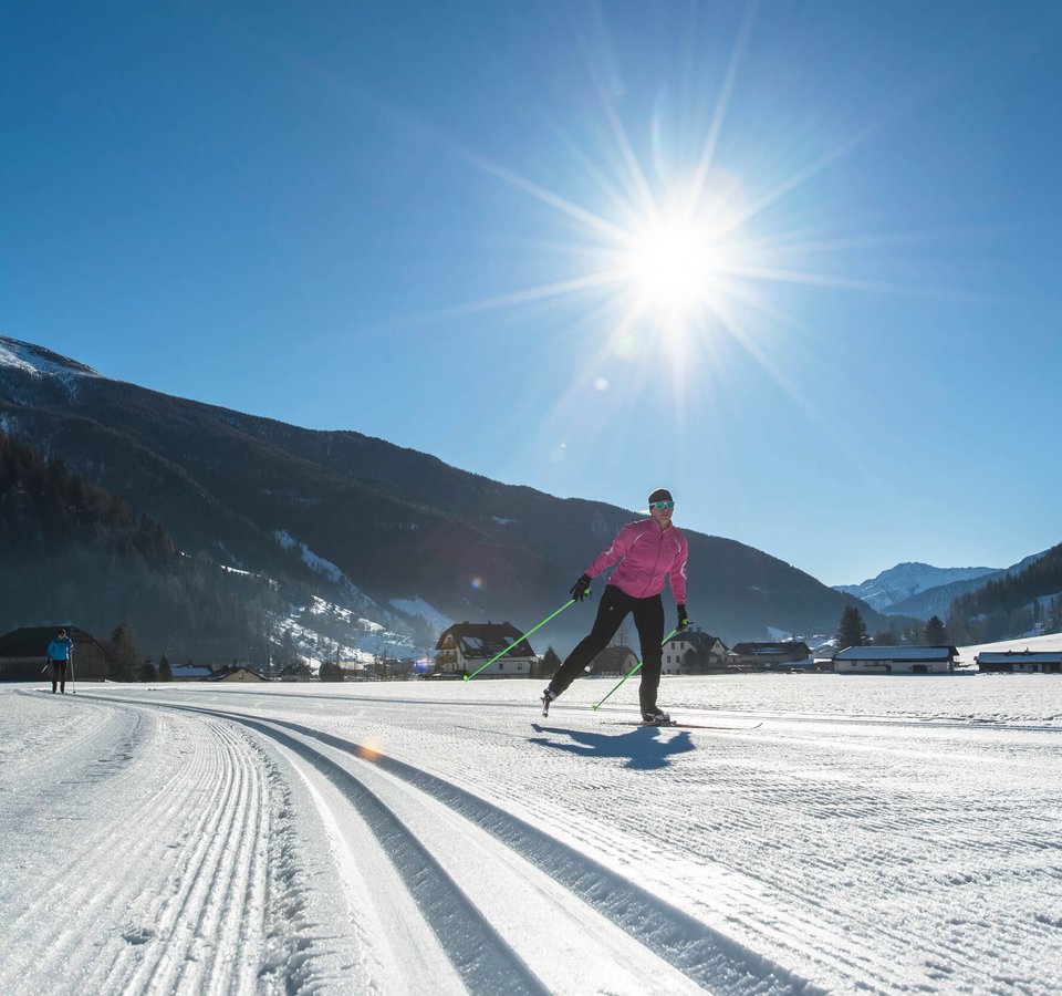 Langläufer bei sonnigem Wetter in verschneiter Berglandschaft