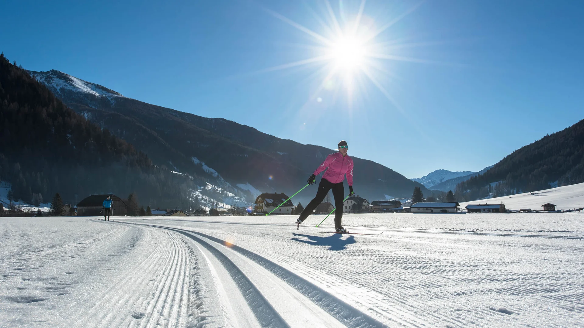 Langläufer bei sonnigem Wetter in verschneiter Berglandschaft